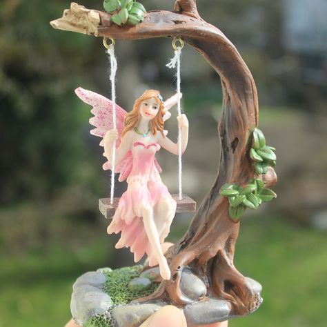 This beautiful, swinging fairy statue made of resin is a must-have addition to any home seeking magic and charm.  The statue depicts a fairy swinging on a tree branch, carried by the gentle breezes. Each movement causes the fairy to gently sway back and forth, lending a calming atmosphere to the room.  This decorative figure is a true work of art and is sure to enchant every visitor.  Place it on a shelf or table to make your home a place full of magic! Material: Resin Size: 14x10 cm (5,5x3,9") Magical Home Decor, Sway Back, Garden Fairies Figurines, Antique Porcelain Dolls, Tree Statues, Fairy Statues, Magical Home, Resin Statue, Calming Atmosphere