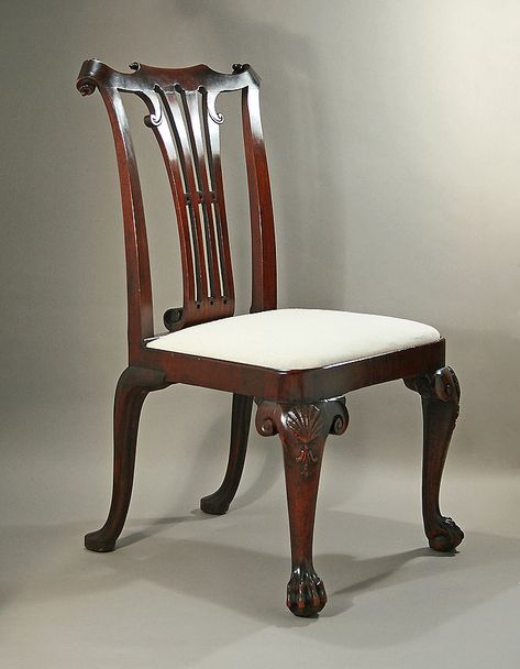 GEORGE II IRISH CUBAN MAHOGANY SIDE CHAIR -   Ireland, c1735. Featuring finely carved paper-scrolls to the yoked crestrail center and volutes above a vertically pierced splat with  further scrolls and circular connectors, ending in a large strongly coiled back-scrolled seatrail attachment (2-3/8” from  splat front to back of scroll); above a rectangular seat and four cabriole legs, the front knees with shells sided by boldly  carved knee returns, above hairy paw feet. 39" H x 23" W x 25" D Paper Scrolls, Wooden Living Room Furniture, Chippendale Furniture, Dining Table Design Modern, Antique Dining Chairs, Carved Chairs, Georgian Furniture, Chair Design Wooden, Colonial Furniture