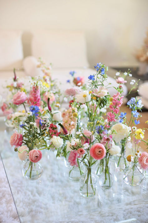 A Picture of Whimsical Bud Vases With Ranunculus, Delphinium, and Roses. Simple Garden Wedding Decorations, Wildflower Wedding Spring, Wildflower Long Table Wedding, Diy Ceremony Flower Arrangements, Wildflowers And Candles Wedding, Wildflower Altar Arrangement, Coastal Wildflower Wedding, Wild Flower Tablescape, Wild Flowers Wedding Table