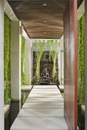 At the front of the villa, an eggshell-white stone path with hanging vines and a large koi pond leads to an Indian slate wall with a waterfall. "In traditional Balinese architecture, the entrance to a home must be facing an interior wall which prevents evil spirits from coming into the home," Mr. Emmerson said. Bali Architecture, Bali House, Tropical Architecture, Real Estat, Entrance Design, Tropical House, House Entrance, Balinese, Outdoor Design