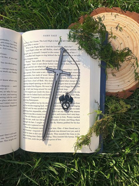 Leather Sword Bookmark, Fantasy Bookmark, Elven-Inspired Bookmark, Gift for Readers, Elf Fairy Faerie Fae Bookmark Make your reading a little extra magical with this beautiful engraved faux leather bookmark with a metal dragon tassel. This bookmark is engraved in my home workshop on faux leather leatherette that engraves into a light silver color and finished with a metal dragon charm. HANDCRAFTED IN THE USA- Made in Los Angeles, California by a small, family-owned business NATURAL VARIATION DIS Faux Leather Bookmark, Bookmark Holder, Fantasy Bookmarks, Dragon Bookmark, Metal Dragon, Elf Fairy, Charm Bookmark, Pretty Knives, Creative Bookmarks