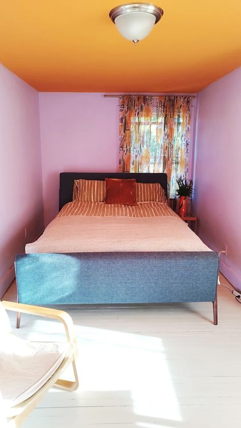 A bed in a nook with purple walls and an orange ceiling decorated with orange pillows. Purple And Orange Bedroom, Colorful Eclectic Bedroom, Orange Ceiling, Orange Rooms, Purple Color Block, Carolina House, Bedroom Orange, Orange Decor, Eclectic Bedroom