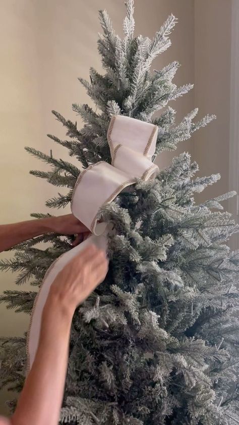 a person is wrapping a white ribbon around a christmas tree