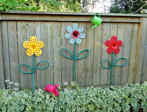 use old hoses and paint some wooden flowers to make these cute garden flowers.  40 Surprisingly Awesome Dollar Store Crafts Backyard Flowers, Pool Fashion, Fence Art, Outdoor Crafts, School Garden, Fence Decor, Creative Gardening, Wooden Flowers, Wooden Fence