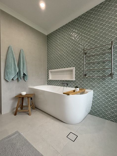 The fish scale tile wall is a stunning focal point, adding texture and movement. The soft green tiles evoke calm oceans, enhancing the spa-like ambiance and perfectly complementing the sleek freestanding bath with a seamless blend of modern and natural elements. Fish Scale Bathroom, Half Tiled Bathroom Walls, Half Tiled Bathroom, Tiled Bathroom Walls, Tiled Feature Wall, Fish Scale Tiles, Scale Tile, Tiled Bathroom, Fish Scale Tile