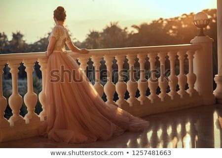 *Dress is not the right period but balustrade and general position are good.* Beautiful lady in luxurious ballroom dress with tulle skirt and lacy top standing on the large balcony looking away at sunset. Back view. Text space Princess On Balcony, Opera Balcony, Princess Balcony Aesthetic, Castle Balcony Aesthetic, Eiffel Tower View From Balcony, Queen Gown, Large Balcony, Lacy Tops, Exquisite Gowns