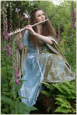 Lovely Renaissance scene of a young woman in long blue dress playing her flute while sitting on a mossy log among the ferns and wildflowers in the forest woods. -DdO:) - http://www.pinterest.com/DianaDeeOsborne/peaceful-people - Pin photo via Jenny Conley Person Playing The Flute Reference, Flute Instrument Aesthetic, Flute Holding Pose, Person Playing Flute, Flute Player Aesthetic, Playing Flute Pose Reference, Flute Pose Reference, Flute Reference, Drape Reference