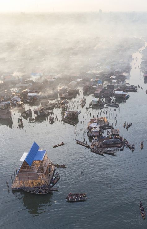 NLÉ | 'Makoko Floating School' | Makoko is a old, sprawling shanty town supported on stilts above the waterfront of Lagos, Nigeria. Increasingly battered by rising seas, the settlement was becoming dangerous, and the government forcibly cleared part of it last year. Kunle Adeyemi, a Nigerian architect, had a better idea. He and his team devised a floating school that provides a flexible and robust prototype for housing and other potential structures. | Lagos, Nigeria | 2013 | www.nleworks.com/ Architectural Review, Floating Architecture, Shanty Town, Sea Shanties, Floating City, Sea House, Lagos Nigeria, Save Animals, Photography Contests