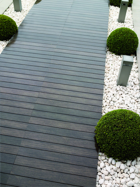 a dark stained wooden path with white pebbles lining and boxwood looks ultra modern and bold