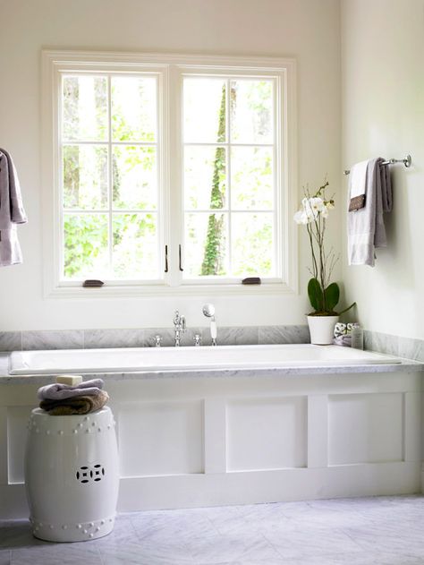 A Nod to Simplicity  This bathtub is a fusion of unrivaled style and understated simplicity. Inconspicuous linen-white walls serve as the backdrop for a sliver of gray stone that wraps around the tub surround. Although small, the detailed faucet and handheld shower fall in line with the simple yet elegant credo of the space. Bathtub Surround Ideas, Bath Under Window, Master Tub, Bathtub Surround, Drop In Tub, Bathtub Design, Bad Inspiration, Tub Surround, Master Bath Remodel