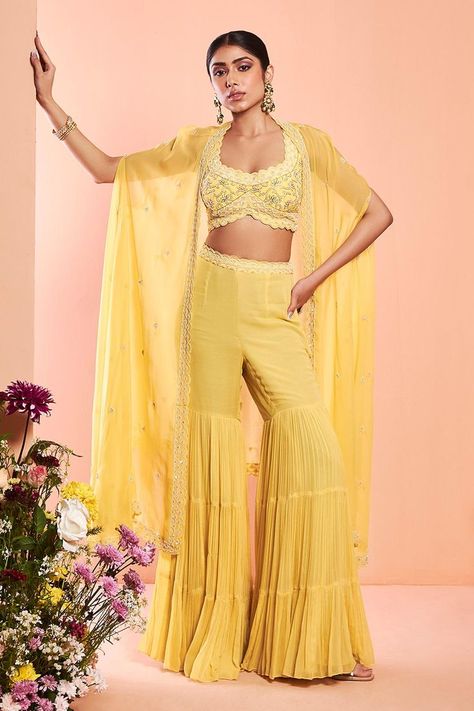 Buy #daisy #yellow embroidered cape with scallop hem. Paired with dabka embroidered blouse and tiered sharara by #NiamhbyKriti at #AzaFashions Shop online now at #Azafashions.com Call +91 8291990059 or email contactus@azafashions.com for enquiries. #wedding #festive #ethnic #tradional #shopping #shoponline #party #reception #bride Women Haldi Outfit, Cape Sharara, Yellow Sharara, Sharara Designs, Beaded Cape, Embroidered Cape, Daisy Yellow, Pearl Work, Yellow Pearl