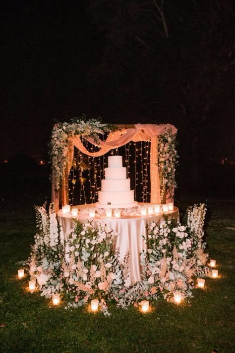 wedding cake display surrounded by flowers Outdoor Wedding Cake Table Ideas, Romantic Wedding Cake Table, Wedding Flower Display Ideas, Simple Cake Backdrop, Outdoor Wedding Cake Table, Cake Displays For Weddings, Wedding Cake Display Table Elegant, Wedding Cake Area Decoration, Candle Decoration Wedding