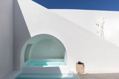 Nella vibrante isola greca di Santorini i sotterranei di una vecchia casa sono stati trasformati in due residenze a Fira, una coppia di case vacanza dello studio Kapsimalis Architects. Come nella tradizione architettonica di Santorini, la facciata esterna è stata mantenuta nelle sue condizioni originali, in modo da non disturbare l'estetica tutta bianca delle case vicine. Non mancano, però, degli inserimenti moderni all'insegna del comfort come questa piscina posta sotto alle scale esterne. Santorini House, White Architecture, Walled Courtyard, Piscina Interior, Cave House, White Building, Minimalist Lighting, Concrete Cement, Patio Interior