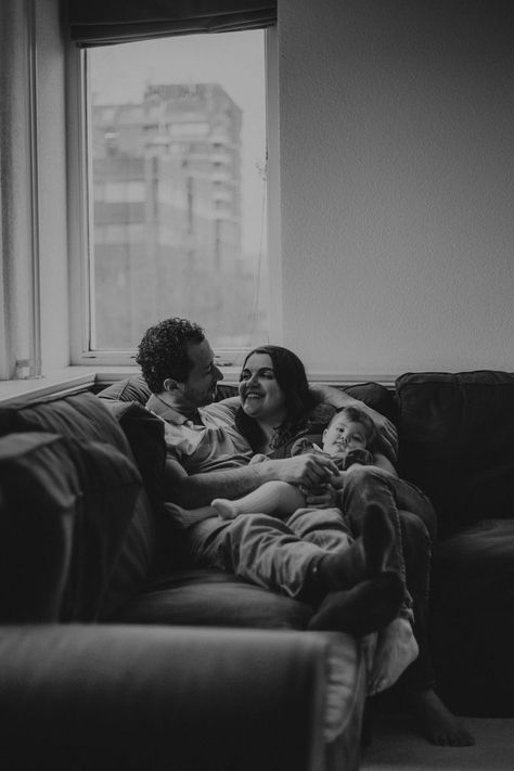 Dad, mom and baby cuddling on the couch I’m Home Family Pictures, Family House Photoshoot, Family Portrait At Home, Cozy Indoor Family Photoshoot, At Home Family Pictures, I’m Home Photo Shoot Family, Loft Photoshoot Ideas, Family Home Photos, Family Home Shoot