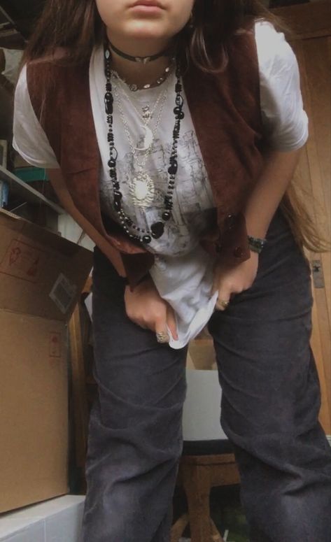 A mid-size person/girl wearing a white wide oversized graphic shirt, a wide dark brown waistcoat, thrifted black corduroy pants, black dr. Martins and multiple crystal rings and bracelets. 	The person is also wearing multiple silver necklaces, one in form of a moon and another in form of a frog necklace and a black lace choker. Brown Waistcoat Outfit Women, Fairy Academia Aesthetic Outfit, Dark Academia Spring Outfit, Earth Core Outfits, Grandpa Core Outfits, Weird Core Outfits, Fairy Core Aesthetic Outfits, Fit Aesthetic Outfit, Nonbinary Style