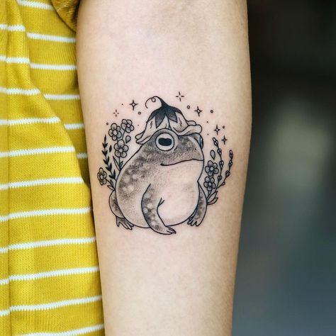 Leah Samuels on Instagram: “Cottagecore bb on @craftmyspirit 🌿 Done at @howdy.la . . . . . . #toad #toadtattoo #cutetattoo #cottagecore #delicatetattoo…” Cottage Tattoo Simple, Frog With Flower Tattoo, Frog Tattoo Flower, Flower Frog Tattoo, Fairy Cottage Tattoo, Small Toad Tattoo, Witch Frog Tattoo, Cottagecore Sleeve Tattoo, Frog Flower Tattoo