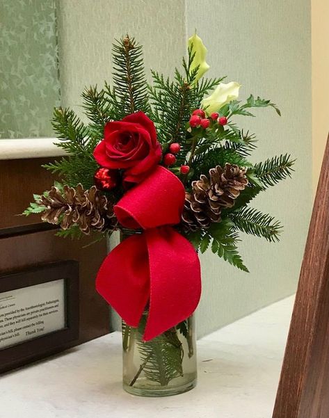 Clear vase with artificial pine greenery. Decorated with a rose, berries, pinecones and ribbon. Your choice of red, burgundy or white rose. Red & white rose comes with red ribbons. Burgundy rose comes with burgundy ribbon. All sales final. Tall Vase Christmas Arrangements, Cheap Holiday Centerpieces, Centerpieces For Christmas, Christmas Vase Arrangements, Christmas Floral Arrangements Diy, Winter Flower Arrangements, Christmas Decorations Centerpiece, Christmas Vases, Christmas Bouquet