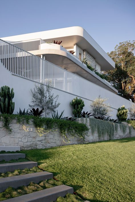 Clare, an ode to the previous owner, is a series of sweeping curved terraces built around an existing pre-war Queenslander, set on an awkward L-shaped sloping inner-city Brisbane block. The design takes advantage of its north aspect, city views, and dual frontage and puts raw materials and landscaping on show.    The concept was to create a home that followed the unique shape of the block, both in plan and in section, taking advantage of the northeast aspect and city views. Moroccan Exterior, Brisbane Architects, Landscaping A Slope, Terrace Building, Home Landscaping, Big Windows, Building Structure, Inner City, Facade House