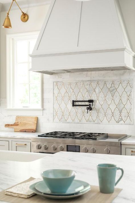 A black swing arm pot filler is fixed to Moroccan trellis cooktop tiles beneath a white wood range hood and over a stainless steel oven range. Accent Tile Kitchen, European Home, Kitchen Backsplash Designs, Moroccan Trellis, Tile Kitchen, Pot Filler, European House, Kitchen Range, White Kitchen Design