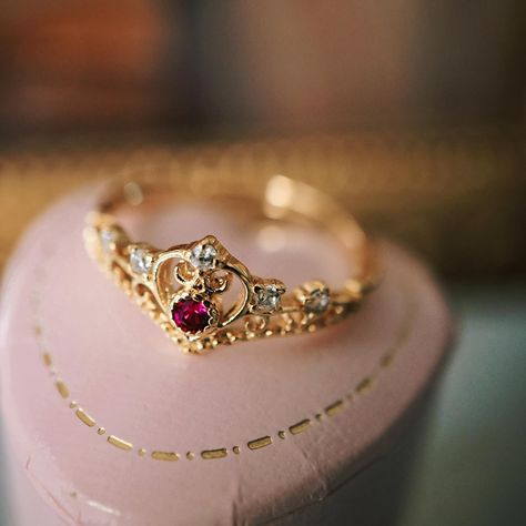 Crafted with exquisite attention to detail, this ring showcases a captivating ruby at its center, surrounded by a halo of shimmering rhinestones. The intricate crown design adds a touch of regal elegance, making it the perfect accessory for any special occasion. Whether you’re a princess at heart or simply looking to add a touch of glamour to your wardrobe, this ring is a must-have. #vintagestyle #vintagejewelry #handmadejewelry #goldjewelry #goldplated #princessring #crownring #ring #rosyco... Ruby Crown, Princess Crown Ring, Crown Ring Princess, Vintage Ring Box, Regal Elegance, Princess Ring, Crown Design, Crown Ring, Vintage Style Jewellery