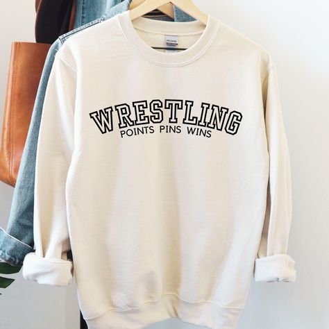 Show off your wrestling pride with our high-quality wrestling sweatshirts, perfect for athletes, fans, and parents alike. These sweatshirts are designed to keep you comfortable and warm, whether you're on the sidelines cheering at a tournament, supporting your team, or gearing up for practice.  Crafted for durability and style, our wrestling apparel is a must-have for anyone passionate about the sport. The bold designs and motivational themes make these sweatshirts ideal for showing your dedication to wrestling, both on and off the mat. Unisex Heavy Blend Crewneck Sweatshirt Ideal for any situation, a unisex heavy blend crewneck sweatshirt is pure comfort. These garments are made from polyester and cotton. This combination helps designs come out looking fresh and beautiful. The collar is r School Wrestling Shirts Ideas, Wrestling Designs For Shirts, Wrestling Sweatshirts, Wrestling Shirts Ideas, Clothing Practice, Wrestling Apparel, High School Sport, Wrestling Mom Shirts, Sideline Cheer