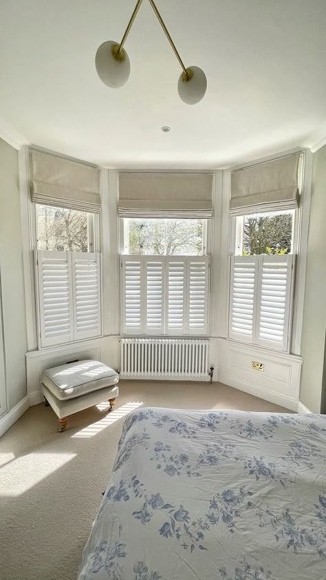 This combination of cafe-style shutters and Roman blinds is just beautiful!  

The cafe-style allows for privacy throughout the day, with the roman blinds in Sila Birch, adding privacy by night with a touch of style!  

The roman blinds also have a blackout interlining allowing increased darkness at night and one which is commonly required with lighter mornings and evenings during Spring and Summer. Roman Blinds Bay Window, Shutters With Curtains, Bedroom Shutters, Bay Window Blinds, Cafe Style Shutters, Shutters Living Room, Bay Window Living Room, Grey Interiors, Bedroom Blinds