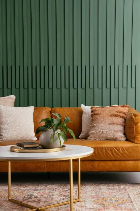 Green Slat Wall with Brown Leather Sofa and Beige Throw Pillows Paneled Walls Living Room, Paint Over Wood Paneling, Interior Board, Slatted Wall, Paneled Walls, Batten Wall, Beige Throws, Beige Throw Pillows, Board And Batten Wall