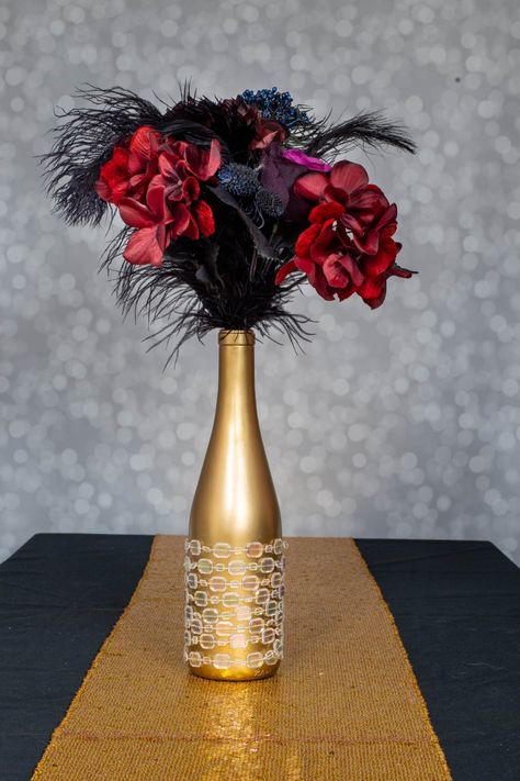 Made with ostrich feathers, wine bottles, faux flowers, champagne glasses, martini glasses and candles, these DIY Gatsby party centerpieces are easy to make and look beautiful. #entertainingdiva #centerpieces #wedding #gatsbyparty Diy Gatsby Party, Great Gatsby Centerpieces, 20s Party Decor, Gatsby Centerpieces, Great Gatsby Party Decorations, 20s Party Decorations, Ostrich Feather Centerpieces, Roaring 20s Wedding, Gatsby Party Decorations