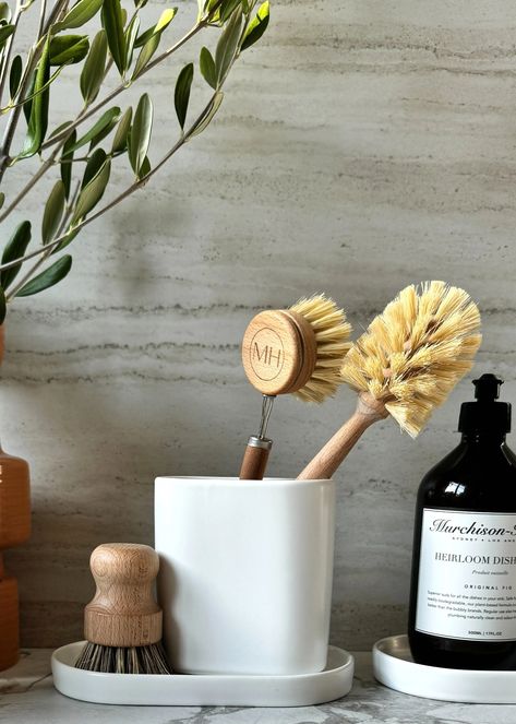 The eternal question for every smart sink-side set-up...where to put the dish brushes and sponge?We solved that little domestic problem with a smart, ceramic brush caddy with built-in drainage (so no mucky water pooling at the bottom of the cup).Use it alone, or pair it with one of our new our Deco Trays. The elegant shape looks good from any angle. Perfect for people with kitchen islands that face out onto a living room.Dishwasher & Microwave Safe.Measurements: 4.5"W x 4.7"H x 2.3"D (11 cm W x 12 cm H x 6 cm D)