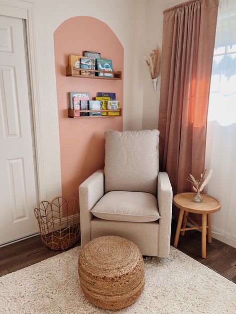 Baby girl boho nursery glider and reading nook Glider Corner Nursery, Boho Nursery Rocking Chair, Nursery Chair Corner Ideas, Book Area Nursery, Nursery Glider Corner, Nursery Book Nook Ideas, Boho Nursery Bookshelf, Baby Nook In Living Room, Small Nursery Corner