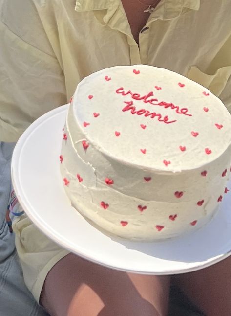 Layered cake with buttercream frosting and red mini hearts with the words “welcome home” written in cursive writing with red icing piped on top of a tall white cake. Welcome Cake For Husband, Housewarming Party Cake, House Warming Aesthetic, No Contact Cake, House Warming Cake Design, Welcome Back Cake Ideas, Frosting Cake Ideas, Welcome Home Cake Design, New Home Cake Ideas