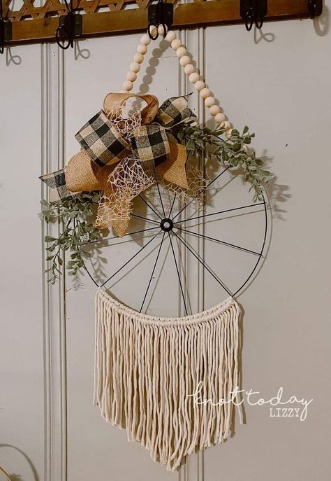 This wreath is giving off simultaneous boho and farmhouse vibes, and I'm loving it. The wood beads and black and white check ribbon on the top somehow balance the macrame fringe on the bottom quite nicely. Wheel Crafts, Diy Wall Hanging Yarn, Wheel Wreath, Macrame Fringe, Easy Fall Wreaths, Farmhouse Vibes, Farmhouse Style Wreath, Diy Fall Decor, Fall Decor Wreaths