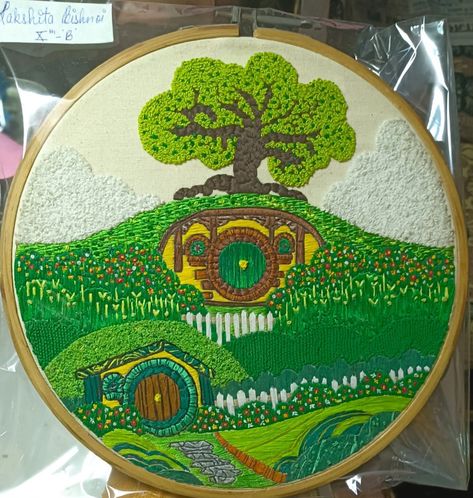 Hey there, this is an embroidery project I made. This is a visit hibbiton poster that I embroidered. It has a lot of greens and the whole scenery is embroidered. Embroidery The Shire, Lord Of The Ring Embroidery, Lord Of The Rings Quilt, Lord Of The Rings Cross Stitch, Hobbit Quilt, Hobbit Embroidery, Lord Of The Rings Crafts, Lord Of The Rings Embroidery, Lotr Embroidery