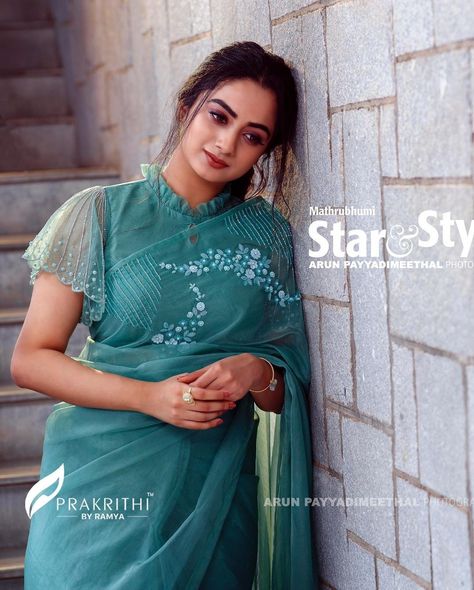 In a teal color saree and sheer high neck cape / cap sleeve blouse design Indian Blouse Designs, Blouse Designs High Neck, Blouse Designs Catalogue, New Saree Blouse Designs, Saree Blouse Neck Designs, Fashionable Saree Blouse Designs, Blouse Back Neck Designs, Blouse Design Images, New Blouse Designs