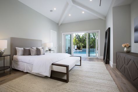 This master bedroom features a shallow vaulted ceiling and a set of sliding glass doors that open out to a pool. Designed by MHK Architecture in Naples, Florida. Mhk Architecture, House Building Ideas, Master Room, Sliding Glass Doors, Coastal Retreat, Bedroom Doors, Master Bedding, Naples Florida, House Building