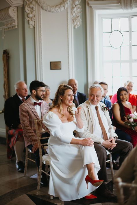 Miss Bush real bride Cat in Jesus Peiro 2214 jumpsuit with culottes, puff sleeves and square neckline for a traditional London pub wedding in Brixton. With red heels and a co-ordinating red lip. #jesuspeiro #bridal #fashion #style #outfit #jumpsuit #trousers #puffsleeves #squareneckline #london #citywedding #shoes #heels #redlip Bride With Red Shoes, Bridal Scarf, Puff Sleeve Wedding Dress, Outfit Jumpsuit, Pub Wedding, Jesus Peiro, Red Bouquet, London Pubs, Bridal Jumpsuit