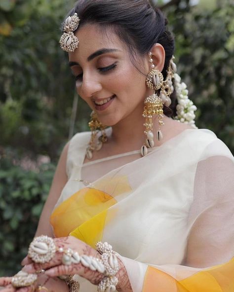 Shell Jewellery For Haldi - Mehendi- Baby shower Brides. 🌸 We customise the set completely according to your needs! 🌸 1) DM US YOUR OUTFIT PICTURE That you'll be wearing For The Ceremony 2) Directly Whatsapp Us On +918006377303. We deliver All Over India 🤗. NOSEPIN KAMARPATTA BAAJUBAND KALEERA etc Are Charged Extra. Customisation of Colours And designs Can be done. . Completely HandMade 💕🌼. . Minimum 10 Days prior Order Basis. . Shipping : 7-10 Working Days. . Contact Us : +918006377303. ... Shell Jewellery For Haldi, Mehendi Photography Bridal, Haldi Look For Bride, Jewellery For Haldi, Traditional Poses, Mehendi Photography, Haldi Ceremony Outfit, Shell Jewellery, Bridal Sarees South Indian