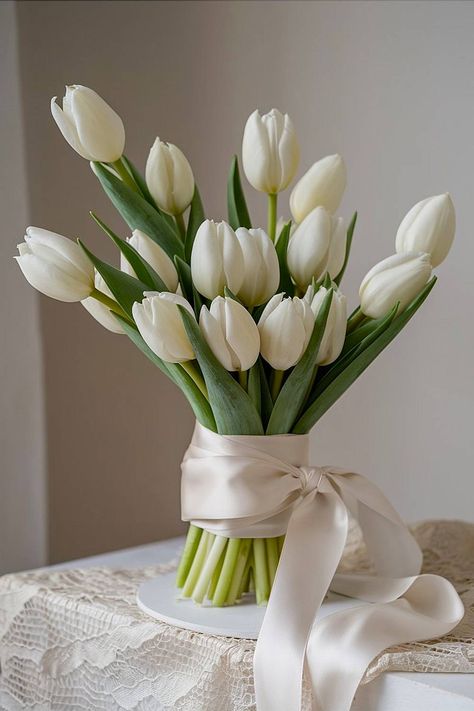 A white tulip bridal bouquet with a satin ribbon wrap. Lily Of The Valley And Tulip Bouquet, Tulip Bride Bouquets, Tulip Wedding Centerpieces, White Tulip Wedding, Wedding Tulips, Tulip Wedding Bouquet, Tulip Bouquet Wedding, Tulip Bridal Bouquet, White Tulip Bouquet