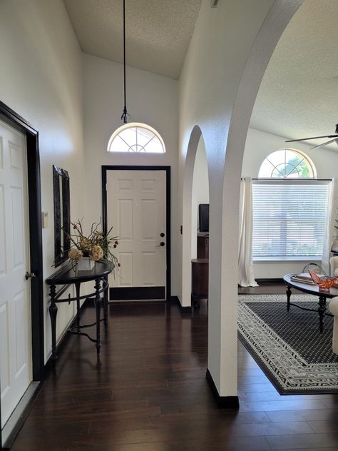 White Wall Black Baseboard, Black Trim With White Doors, White Walls Black Skirting Board, Black Baseboards White Walls, White Walls Black Baseboards, White Doors With Black Trim, White Doors Dark Trim, White Living Room With Black Trim, Painting Baseboards And Trim