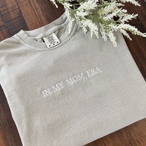 Represent your "mom era" in this 100% ring spun cotton T-shirt! Comfort Colors styles are garment dyed for that soft lived in feel. Choose your color and size (see photos for color and size chart). All orders are stitched in the USA with love! If you do not choose a thread color, white  will be stitched (Black will be stitched on Ivory). Mom Tshirt Ideas, In My Mom Era, Mom Era, Embroidered Tshirt, Embroidered Shirt, Mama Shirt, Perfect Shirt, Black Tshirt, My Mom