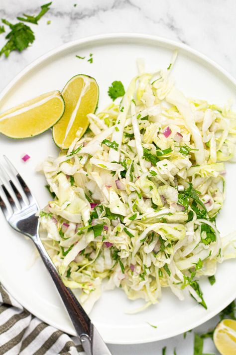 This Cilantro Lime Slaw is the perfect addition to any taco! Crisp, crunchy, and, tangy, it comes together in about 5 minutes and is loaded with all real ingredients - and NO MAYO! This slaw is tossed in a Mexican-inspired lime vinaigrette which leaves it tasting light, zesty, and refreshing! Slaw For Tacos, Lime Slaw, Cilantro Lime Slaw, Lime Vinaigrette, Savoy Cabbage, Vegetarian Side Dishes, Vegetarian Cabbage, Mexican Dinner, Coleslaw Mix