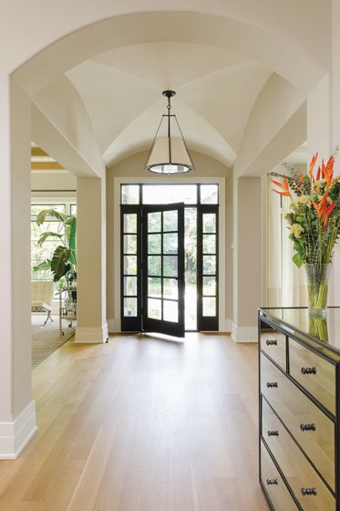 Architectural elements such as a cross-barrel vaulted ceiling and columns define the foyer. Entryway Vaulted Ceiling, One Story Foyer, Arched Foyer Entryway, Groin Ceiling Ideas, Vaulted Ceiling Hallway, Curved Vaulted Ceiling, Vaulted Ceiling Foyer, Single Story Foyer, Vaulted Ceiling Entryway