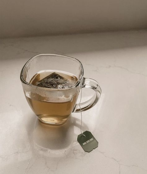 A glass mug with a tea bag inside on a marble countertop. Drink Tea Aesthetic, Hot Drink Aesthetic, Glass Of Tea Aesthetic, Tea Drinker Aesthetic, Morning Tea Aesthetic, Hot Tea Aesthetic, Drinking Tea Aesthetic, Cup Of Tea Aesthetic, Hot Drinks For Winter Aesthetic