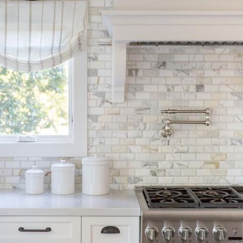 Calcutta gold marble beveled brick backsplash tiles in a transitional kitchen combined with white shaker cabinets, light gray quartz countertops and a white wood panel range hood. Oil rubbed bronze handles and pulls accent the cabinets with the perfect contrast in a popular hardware choice.  Design by Fletcher Rhodes  #kitchenbacksplash #backsplashtile #tilebacksplash #backsplashtile #calcuttagold #calcuttagoldmarble #tilework #tilelove #tileshop #tiledesign #tileart #tileinspo #tileinspiration White Brick Backsplash, Brick Tile Backsplash, Kitchen Cabinets And Backsplash, Backsplash Kitchen White Cabinets, White Wood Paneling, Brick Backsplash Kitchen, Beveled Subway Tile, White Shaker Cabinets, Brick Backsplash