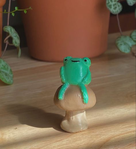 smiling clay frog on toadstool. Frog Modelling Clay, Clay Frog With Hat, Cute Frog Sculpture, Tiny Clay Frog, Clay Ideas Mushroom, Clay Frog Ideas, Clay Frog Tutorial, Air Dry Clay Frog, Frog Clay Sculpture