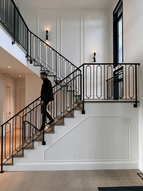 Ornate black steel railing on a grand staircase in front of white walls. Grand Staircase Modern, Modern Staircase Railing Unique, Railing Stairs Design, Iron Railings Indoor, Black Steel Railing, Metal Staircase Railing, Railings For Stairs, Nigeria House, Modern Staircase Railing