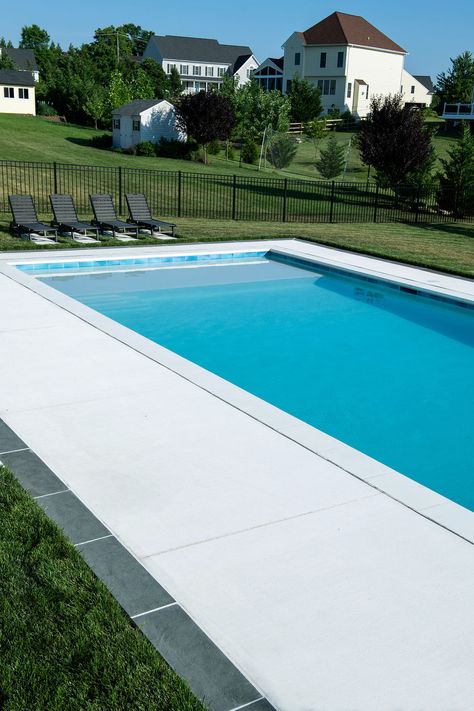 The white concrete pool deck shines bright in this clean, modern design. Sand Finish Concrete Pool Deck, White Concrete Pool Deck, Pool Concrete Colors, Pool Deck Concrete Ideas, Pool Concrete Deck Ideas, White Concrete Pool, White Concrete Patio, White Pool Deck, Concrete Around Pool Ideas