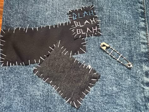 Black and grey fabric sewn onto blue jeans. A patch that reads blah blah blah written in blue, white, and pink is also sewn on. A safety pin is attached next to the 3 pieces of fabric. Punk Safety Pins Fashion, Pins On Pants, Sewn On Patches, What To Do With Safety Pins, Diy Punk Jeans, Patch Jeans Punk, Safety Pin Outfits, Punk Pins Diy, Punk Crafts Diy