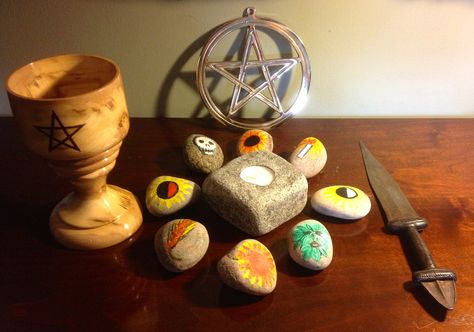 A simple altar set up with The Cup representing the Goddess and the Knife the God. The stones in a circle are called anchor stones, they each represent the different festivals through the year and in the middle is a candle representing the flame of inspiration. The Pentacle at the back represent s the five elements of creation, Earth, Air, Fire, Water and Spirit. Pagan Lifestyle, Sacred Circle, Pagan Rituals, Healing Recipes, Home Altar, Altar Decorations, Kitchen Witch, How To Do Yoga, Book Of Shadows