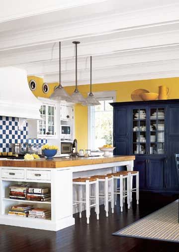 Cottage Modern- Open shelves at one end of this island are a handy place to keep cookbooks. Seating for four was arranged opposite the range with enough overhang so stools can be pushed underneath. The island is lit with three pendant lights overhead. Kitchen With Yellow Walls, Kitchen Color Yellow, Kitchen Yellow, Trendy Kitchen Colors, Blue Shelves, Yellow Kitchen Decor, Серая Кухня, Cottage Modern, Shelves Ideas